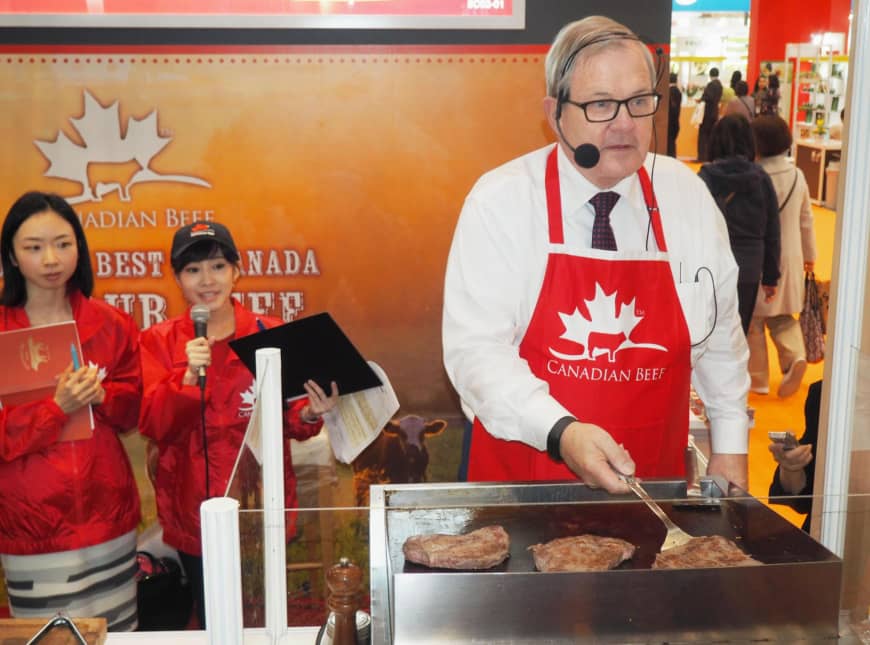 Lawrence MacAulay, Canadian Minister of Agriculture and Agri-Food, grills Canadian beef at the Foodex Japan food trade fair held in the city of Chiba in March. Canada is eager to boost exports of farm produce to Japan under a new Pacific trade pact that no longer includes the United States. | KYODO