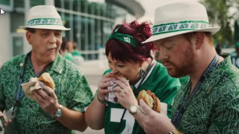 Fans wearing Saskatchewan Roughriders garb eat the Beyond Meat Burger from A&W outside of Mosaic Stadium in Regina in a screengrab from a recent commercial. The Roughriders club has issued an apology to cattle producers in Saskatchewan after concerns were raised about the ad. (A&W/YouTube)