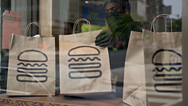 An employee wearing a protective mask picks up a take-out order at Shake Shack. Photographer: Andrew Harrer/Bloomberg , Bloomberg