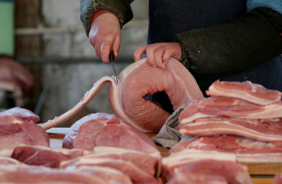 A butcher cuts a piece of pork at a market in Beijing, China /Jason Lee